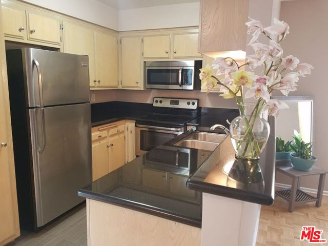 a kitchen with stainless steel appliances granite countertop a refrigerator a stove a microwave a sink and white cabinets