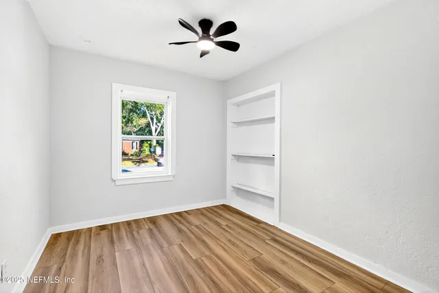 an empty room with windows and ceiling fan