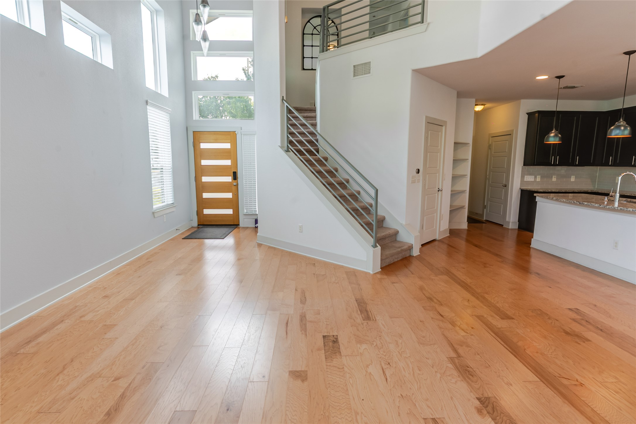1400 Homespun Road Austin, TX 78745 - Photo 8 of 30 Hardwood floors and soaring two-story windows define this airy open-concept entryway.