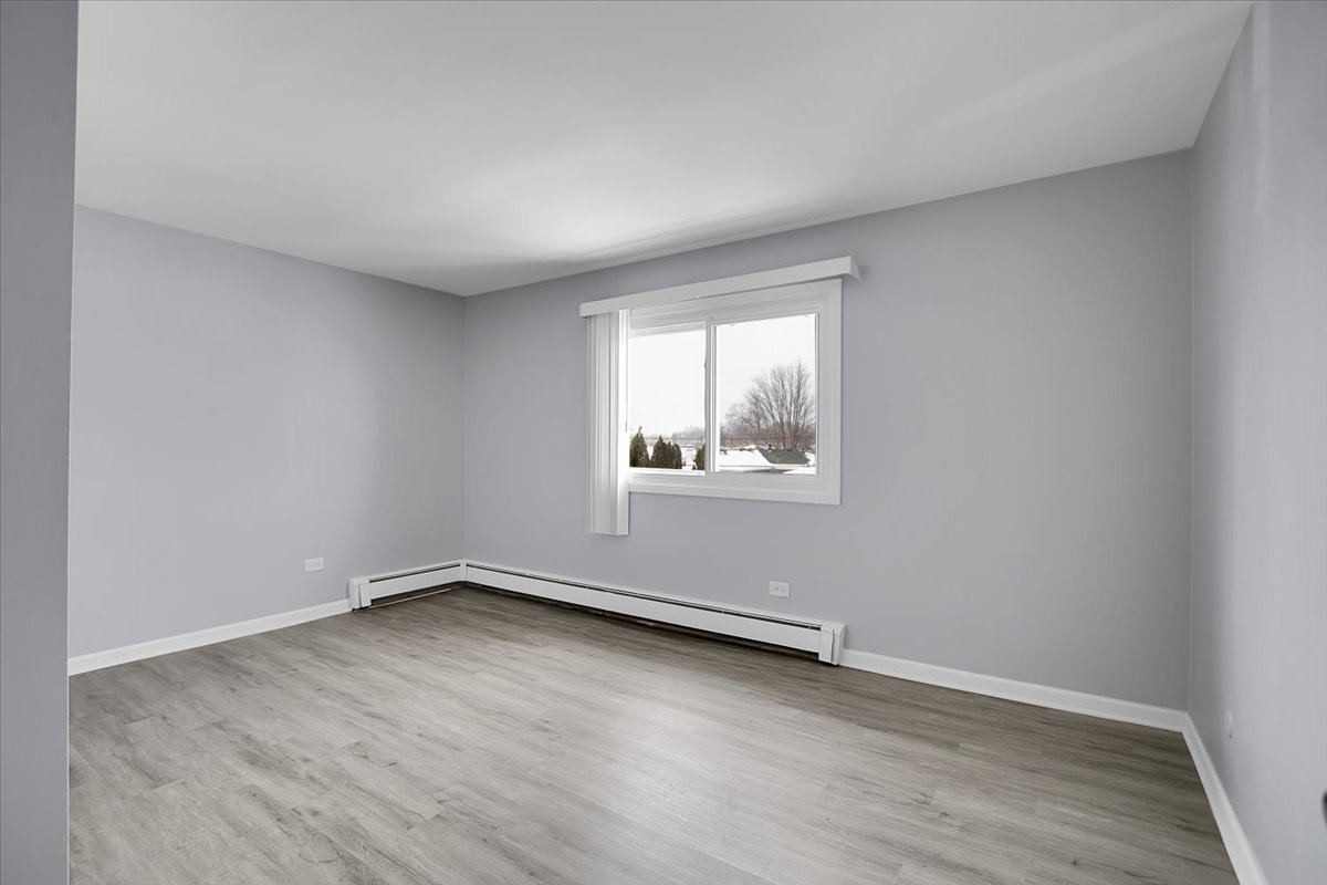 10310 Ridgeland Avenue, Unit 208 Chicago Ridge, IL 60415 - Photo 17 of 29 an empty room with wooden floor and windows