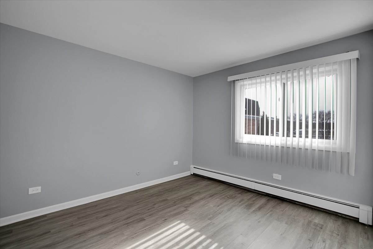 10310 Ridgeland Avenue, Unit 208 Chicago Ridge, IL 60415 - Photo 20 of 29 a view of an empty room with wooden floor and a window