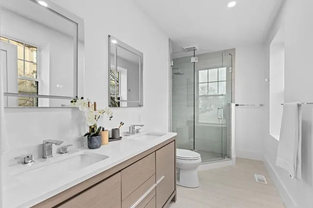 a bathroom with a double vanity sink toilet mirror and shower