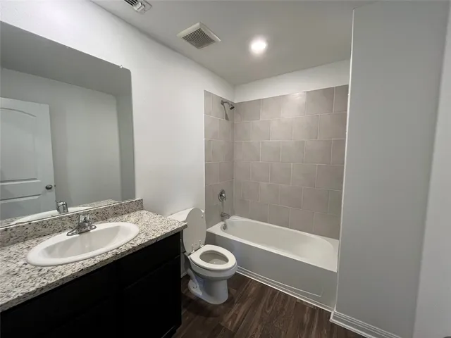 a bathroom with a granite countertop sink toilet a mirror and a bathtub