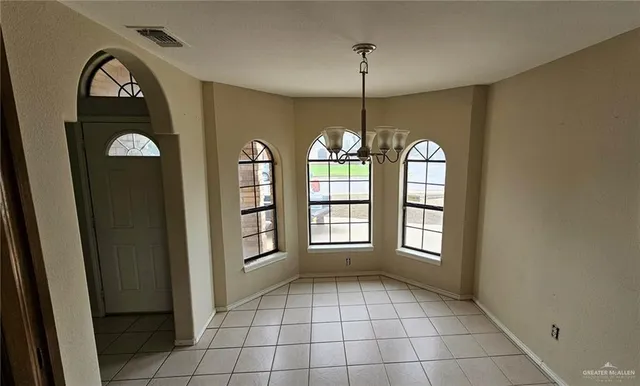 a view of an empty room with window and chandelier fan