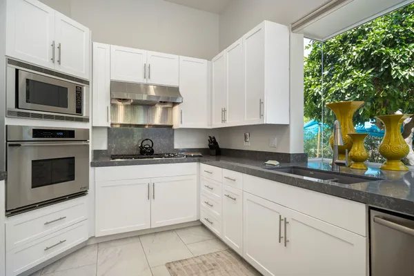 a kitchen with stainless steel appliances granite countertop white cabinets granite counter tops and a wooden floors