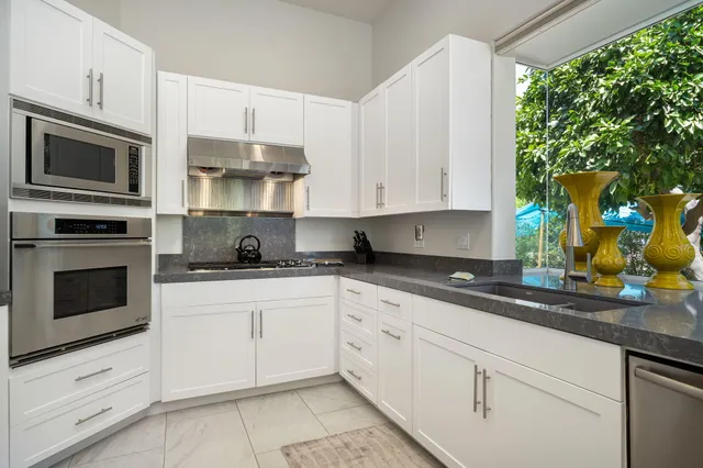 a kitchen with stainless steel appliances granite countertop white cabinets granite counter tops and a wooden floors