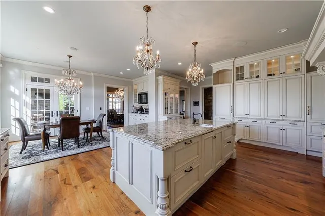 a large kitchen with kitchen island granite countertop a large island in the center and a chandelier