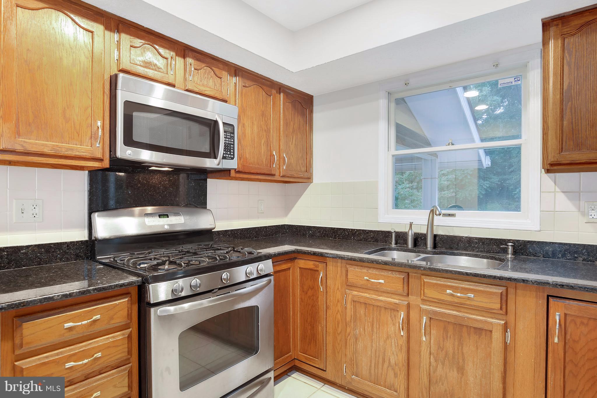 14908 Windmill Terrace Silver Spring, MD 20905 - Photo 7 of 30 a kitchen with granite countertop a sink stove and microwave