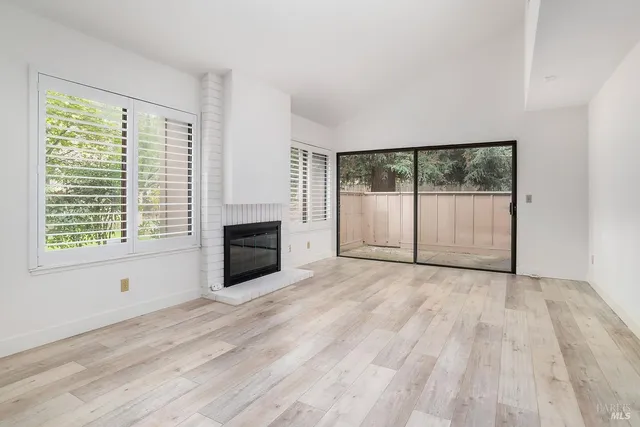 a view of empty room with wooden floor and fireplace