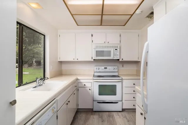 a kitchen with kitchen island white cabinets white stainless steel appliances with a sink and dishwasher