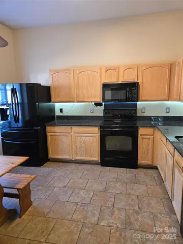 a kitchen with granite countertop a stove top oven and cabinets
