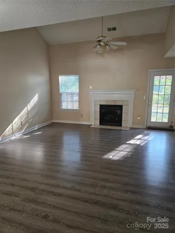 an empty room with wooden floor fireplace and windows