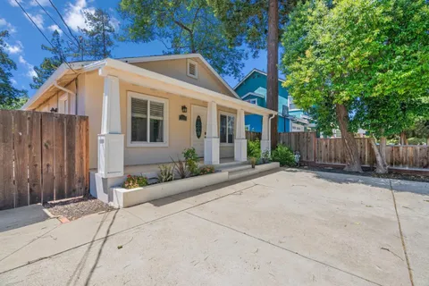 a view of a white house with wooden fence next to a yard