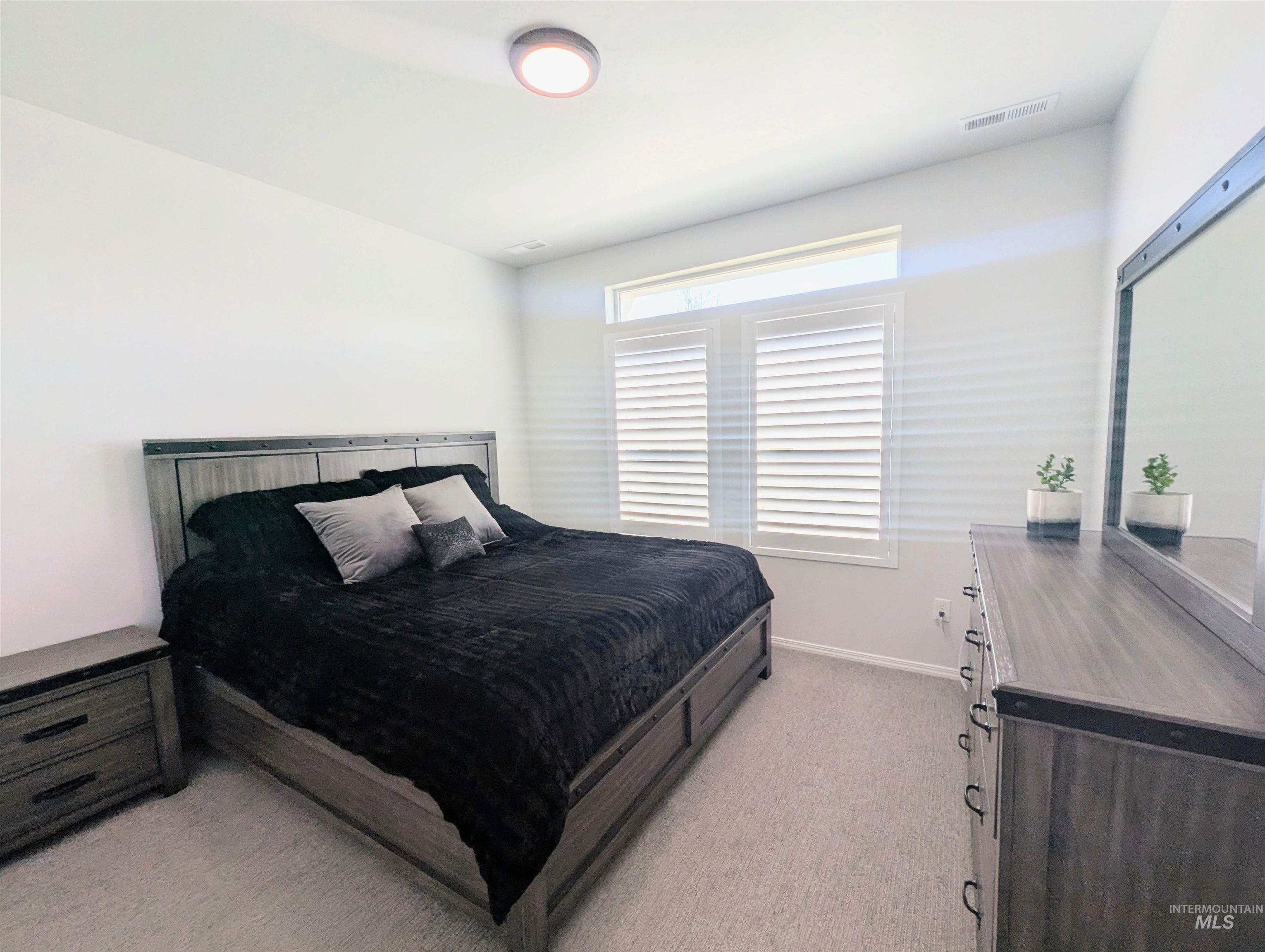 2708 East Buckaroo Drive Kuna, ID 83634 - Photo 28 of 48 Bedroom featuring light gray carpeting, neutral wall paint, and a window with white louvered shutters and an upper transom
