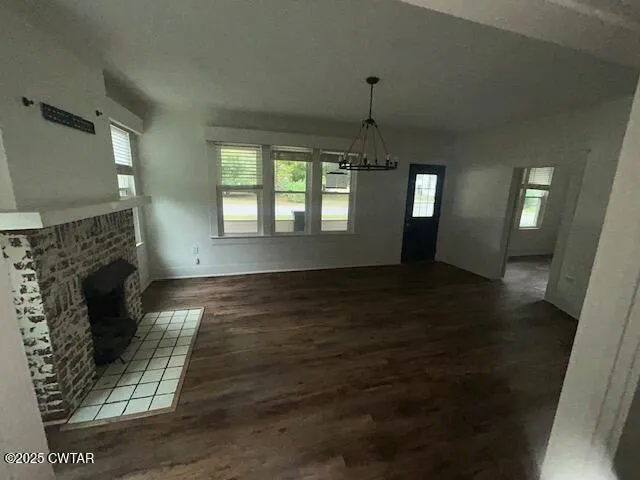 an empty room with wooden floor fireplace and windows