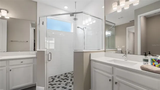 a bathroom with a double vanity sink mirror and shower