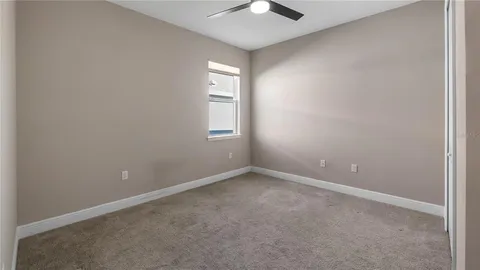 an empty room with windows and chandelier fan