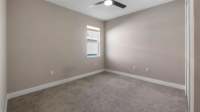 an empty room with windows and chandelier fan
