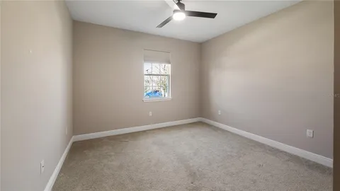 an empty room with a window and a fan