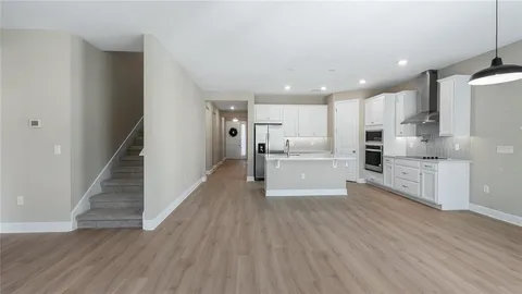 a large white kitchen with wooden floors stainless steel appliances