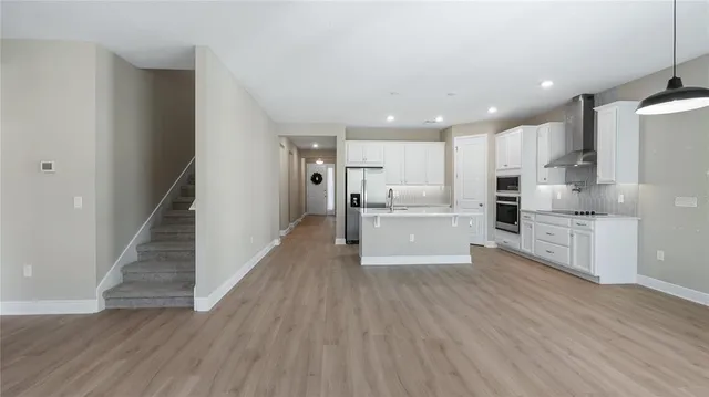 a large white kitchen with wooden floors stainless steel appliances