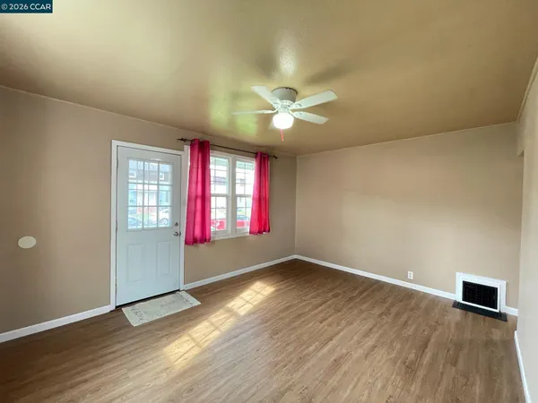 an empty room with wooden floor and windows