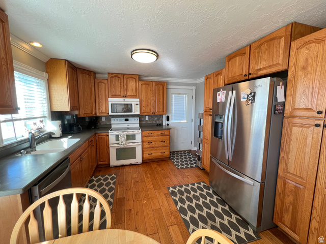 1852 East 3500th Street South Vernal, UT 84078 - Photo 13 of 46 Kitchen with wood finish cabinetry, stainless steel and white appliances, dark countertops, light wood-style floors, and crown molding