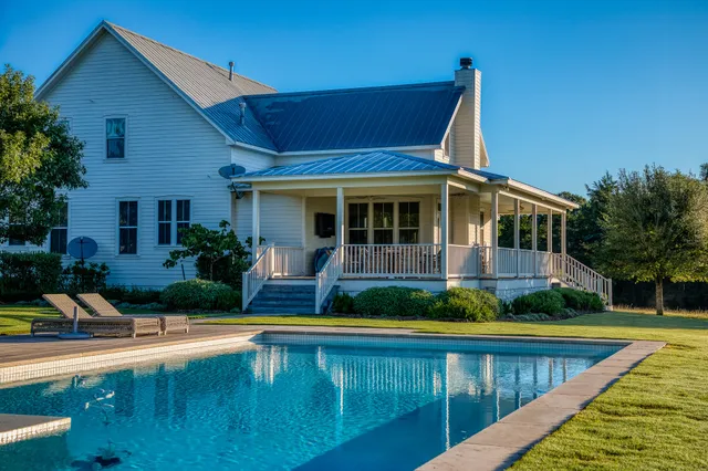 a view of house with swimming pool and yard