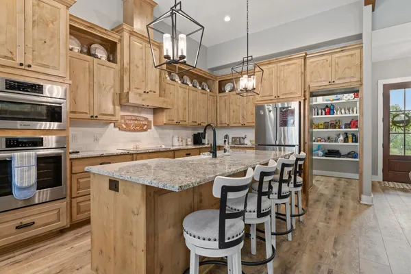 a kitchen with stainless steel appliances granite countertop a stove top oven a sink a dining table and chairs with wooden floor