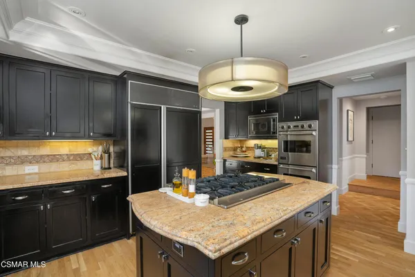 a kitchen with stainless steel appliances granite countertop a sink a stove and a wooden floors