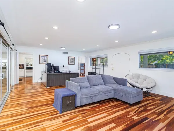a living room with furniture kitchen view and a wooden floor