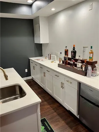 a kitchen with a sink dishwasher and white cabinets with wooden floor