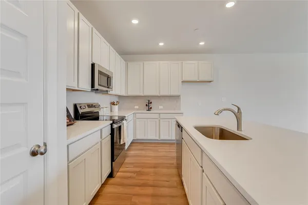 a room with stainless steel appliances granite countertop a sink and a wooden floor
