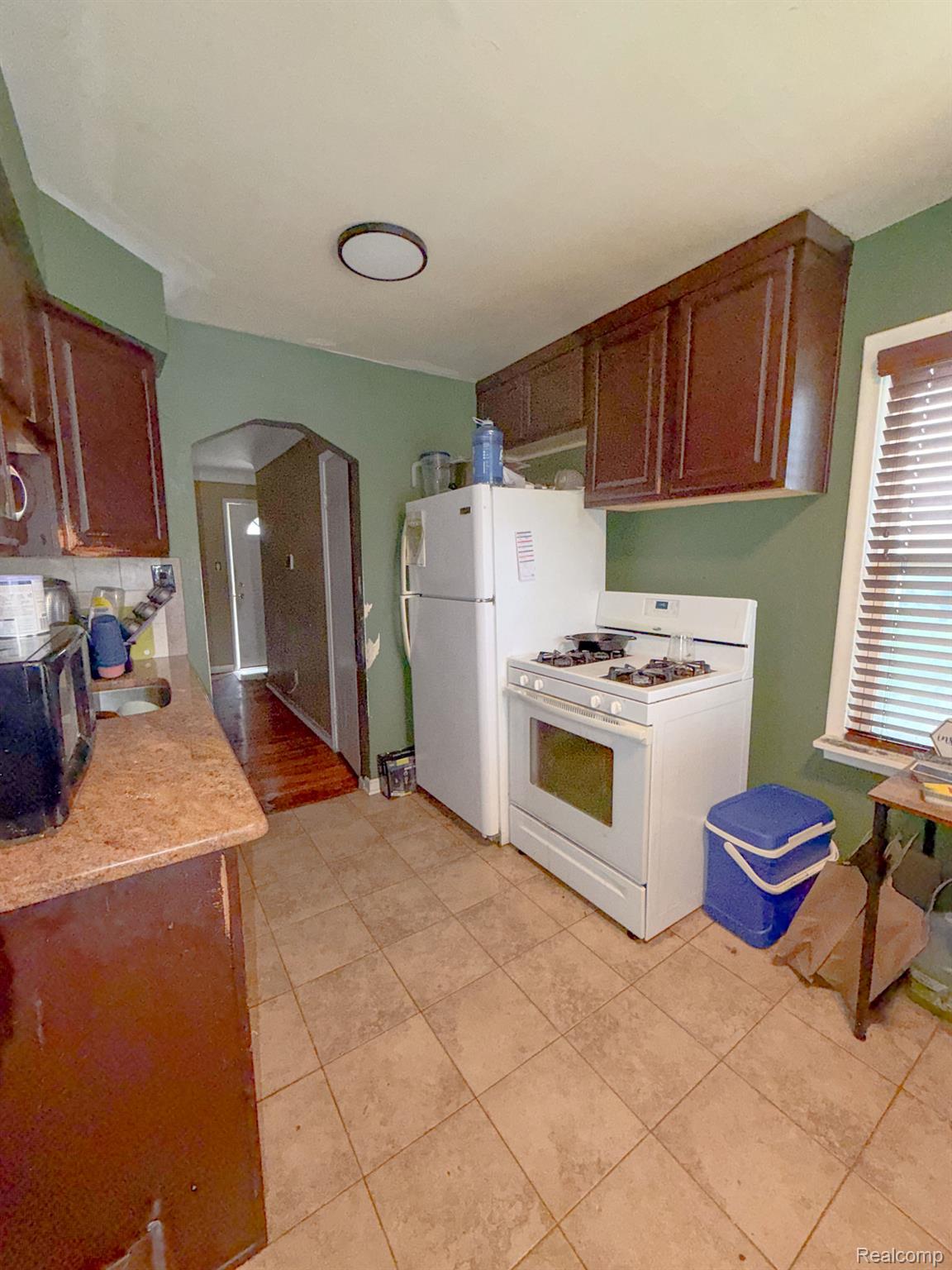 24811 Valley Avenue Eastpointe, MI 48021 - Photo 5 of 22 Kitchen with arched walkways, white appliances, light tile patterned floors, and light stone countertops