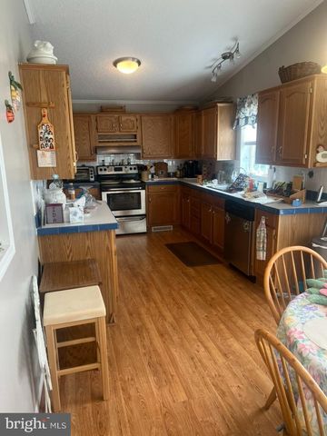 a kitchen with stainless steel appliances kitchen island granite countertop a stove top oven a sink a dining table and chairs with wooden floor