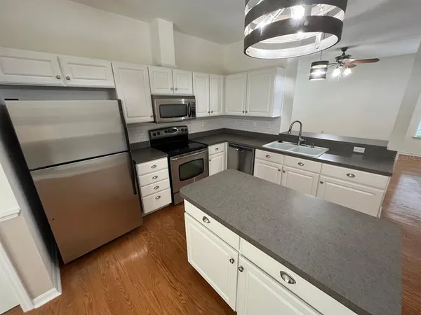 a kitchen with granite countertop a refrigerator a stove and a sink