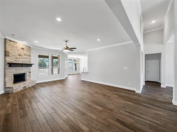 an empty room with wooden floor fireplace and windows