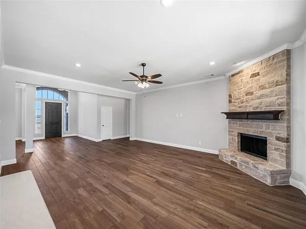 a view of an empty room with wooden floor fireplace and a window