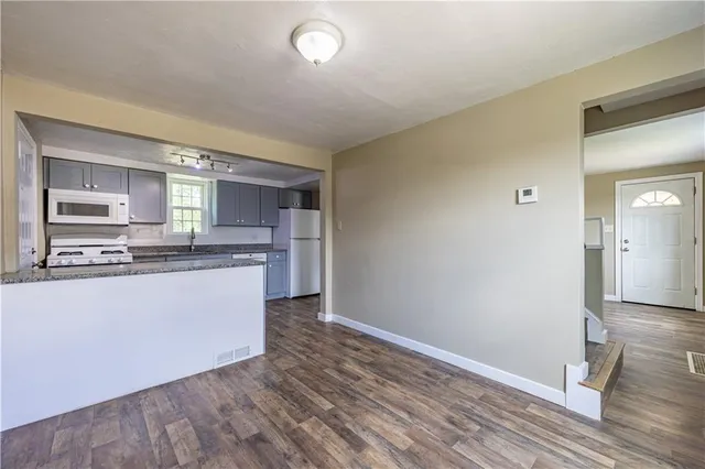 a kitchen with granite countertop a refrigerator and a stove top oven