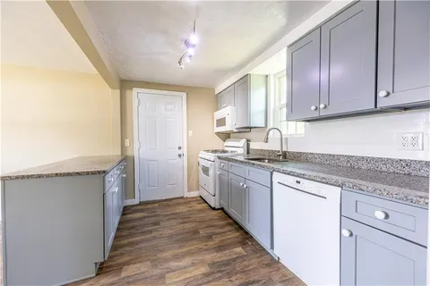 a kitchen with granite countertop wooden cabinets a sink and dishwasher
