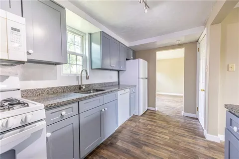 a kitchen with stainless steel appliances granite countertop a stove a sink and a refrigerator with wooden floors