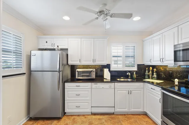 a kitchen with granite countertop a refrigerator a sink a stove a microwave and cabinets