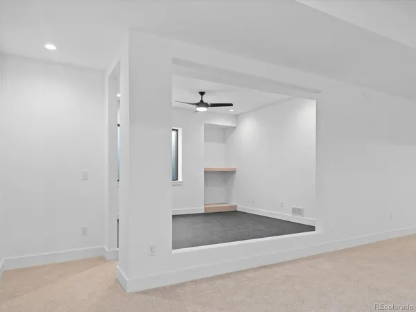 an empty room with a ceiling fan and windows