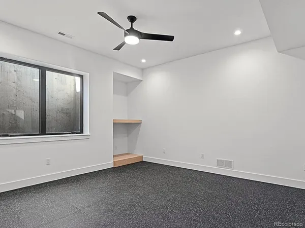 an empty room with a window and ceiling fan