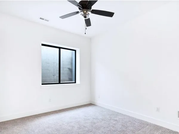 an empty room with a window and a ceiling fan