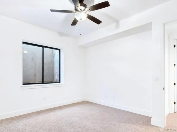an empty room with a window and a fan