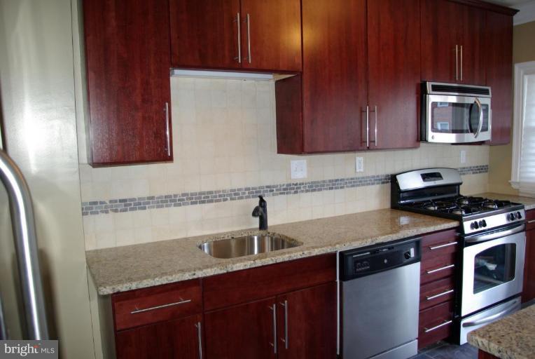 4676 Marble Hall Road Baltimore, MD 21239 - Photo 18 of 20 a kitchen with stainless steel appliances granite countertop a sink stove and microwave