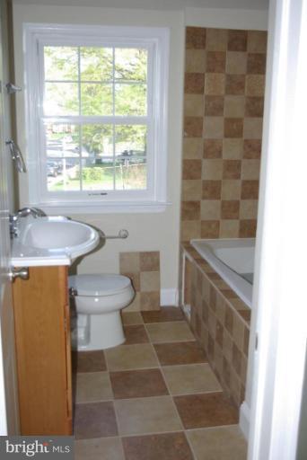 4676 Marble Hall Road Baltimore, MD 21239 - Photo 9 of 20 a bathroom with a granite countertop sink a toilet and a bathtub