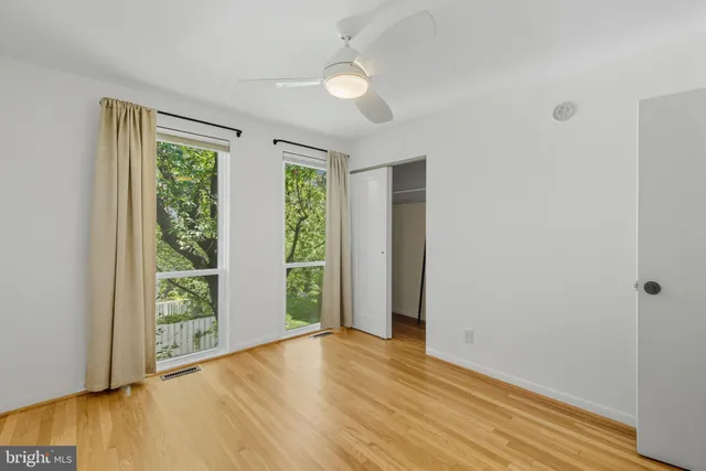an empty room with wooden floor and windows