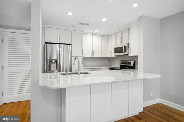 a kitchen with kitchen island granite countertop a sink a stove a refrigerator and white cabinets